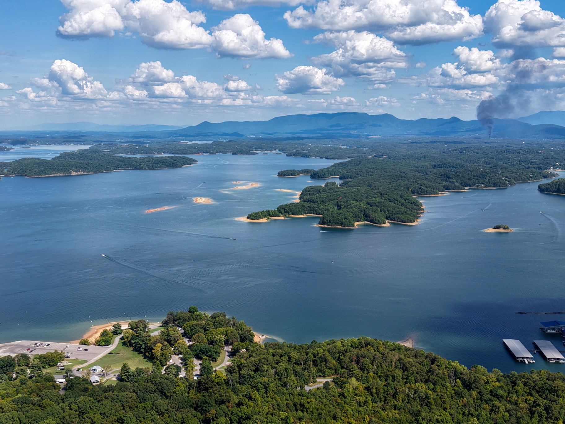 Aerial view of expansive lake with forested islands and distant Smoky Mountains