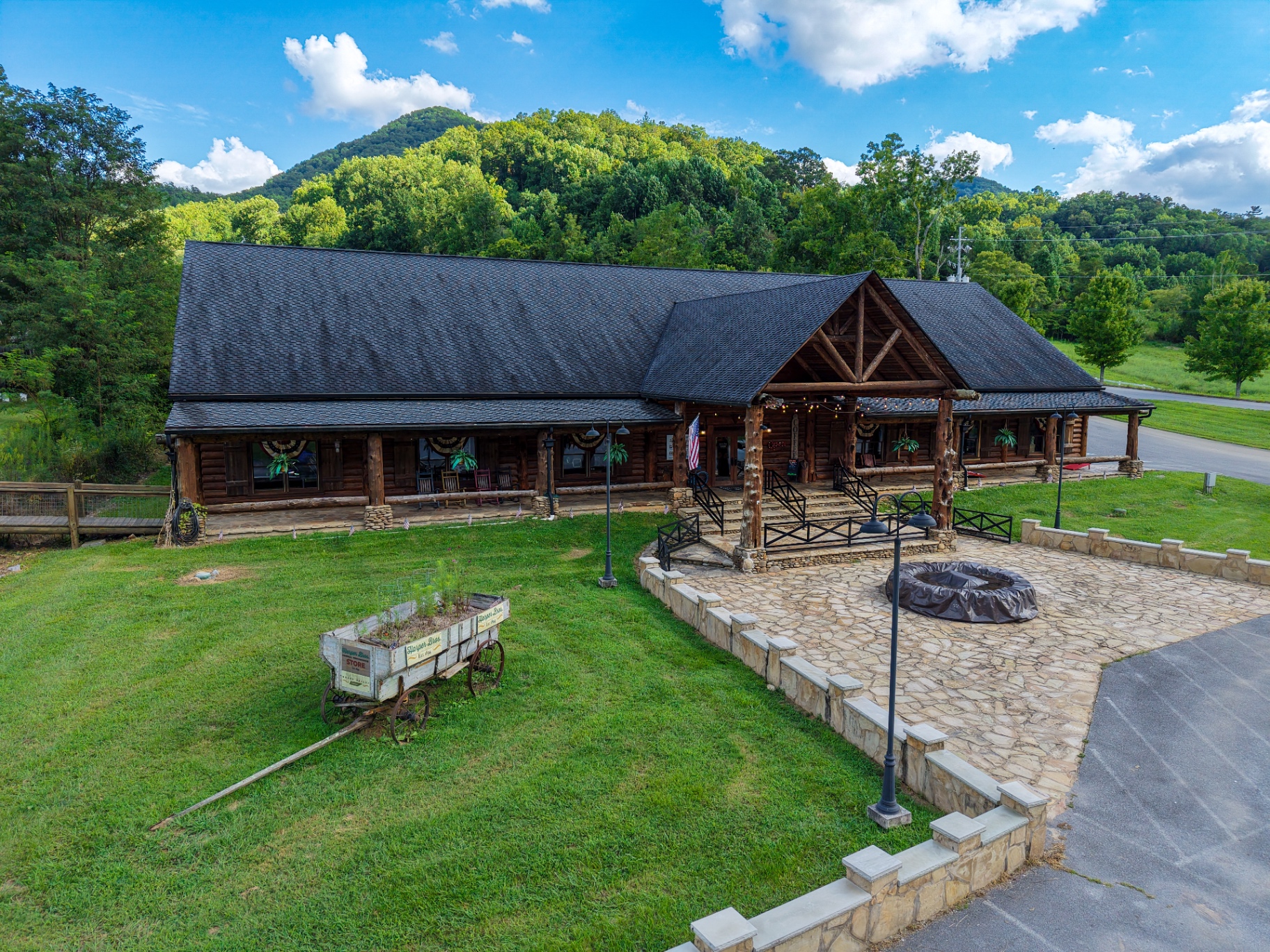 Aerial view of rustic log lodge with stone patio and mountain backdrop