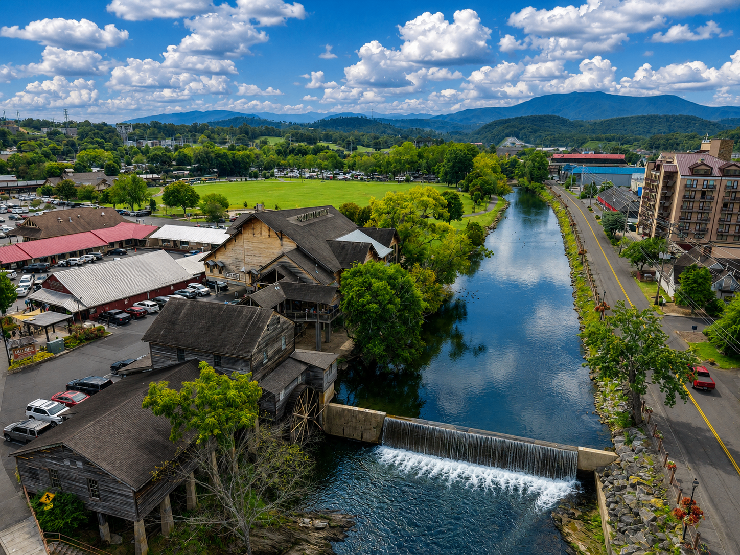 Aerial view of historic riverside mill with waterfall and Smoky Mountains